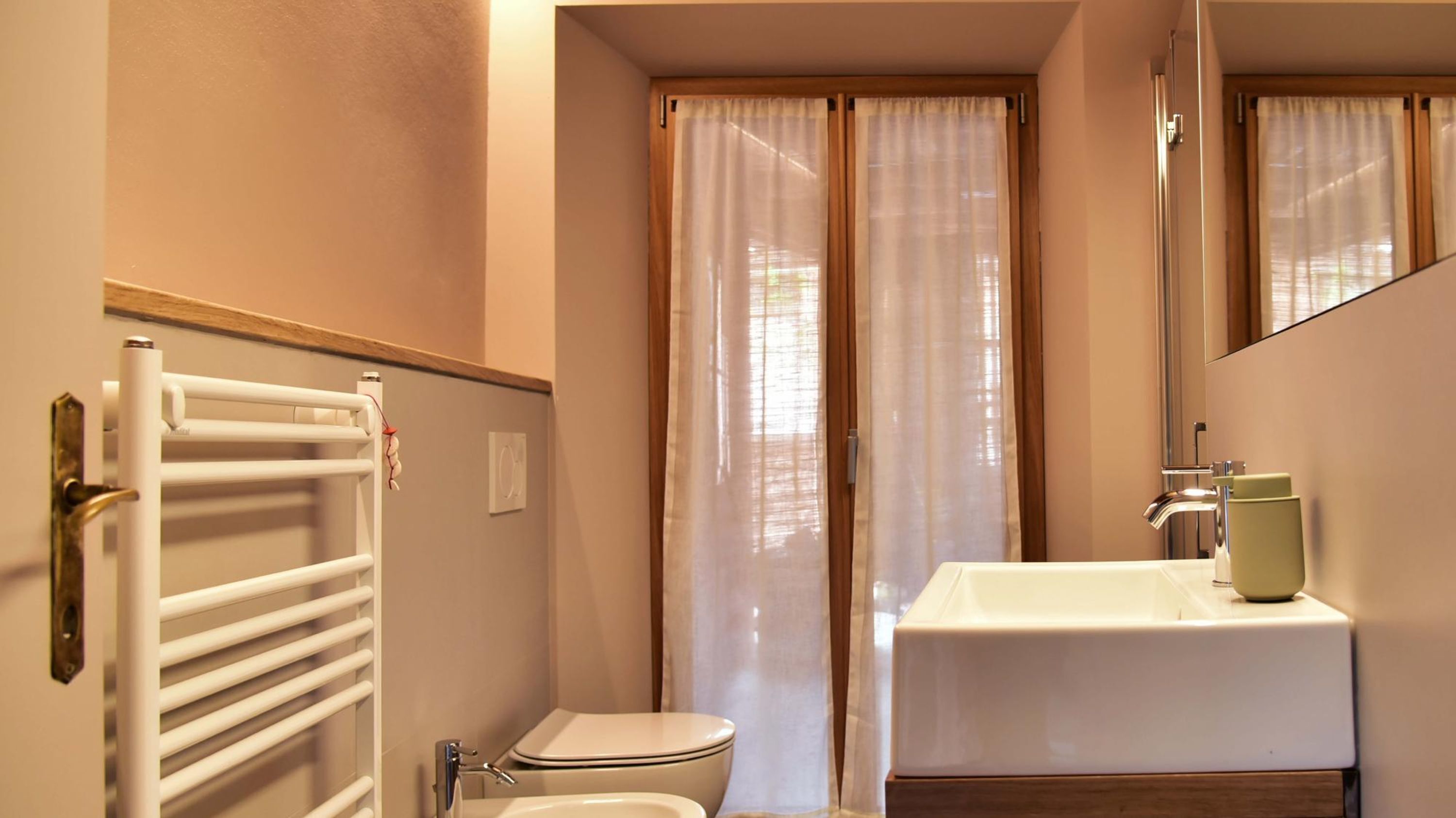Un baño con inodoro, lavamanos y perchero para toallas.