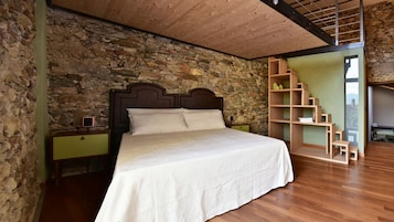Un dormitorio con pared de piedra, techo de madera y cama con cabecero de madera.