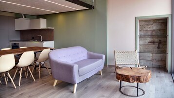 Una cocina moderna con comedor, un sofá púrpura y una silla de madera rústica.