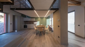 Cozinha moderna com área de refeições, piso de madeira e escada para um andar superior.