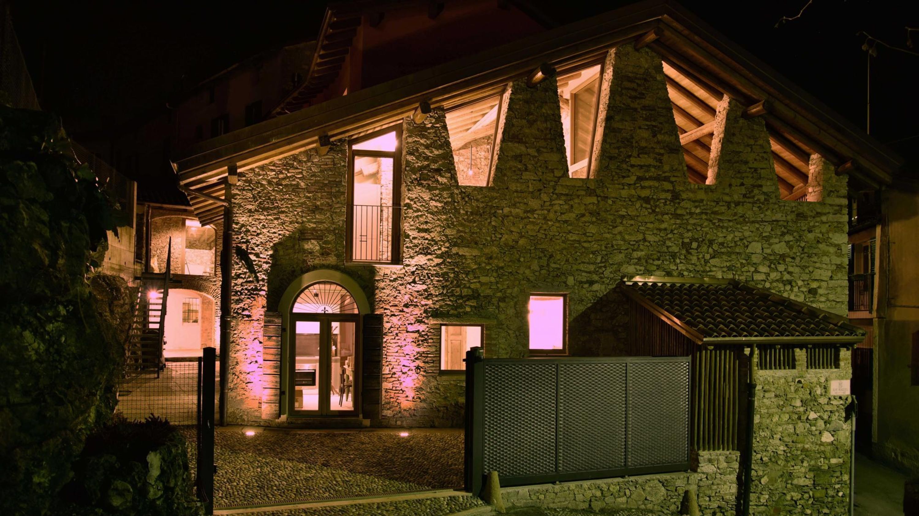 Een stenen gebouw met een houten gevel, een hek en een klein terras.