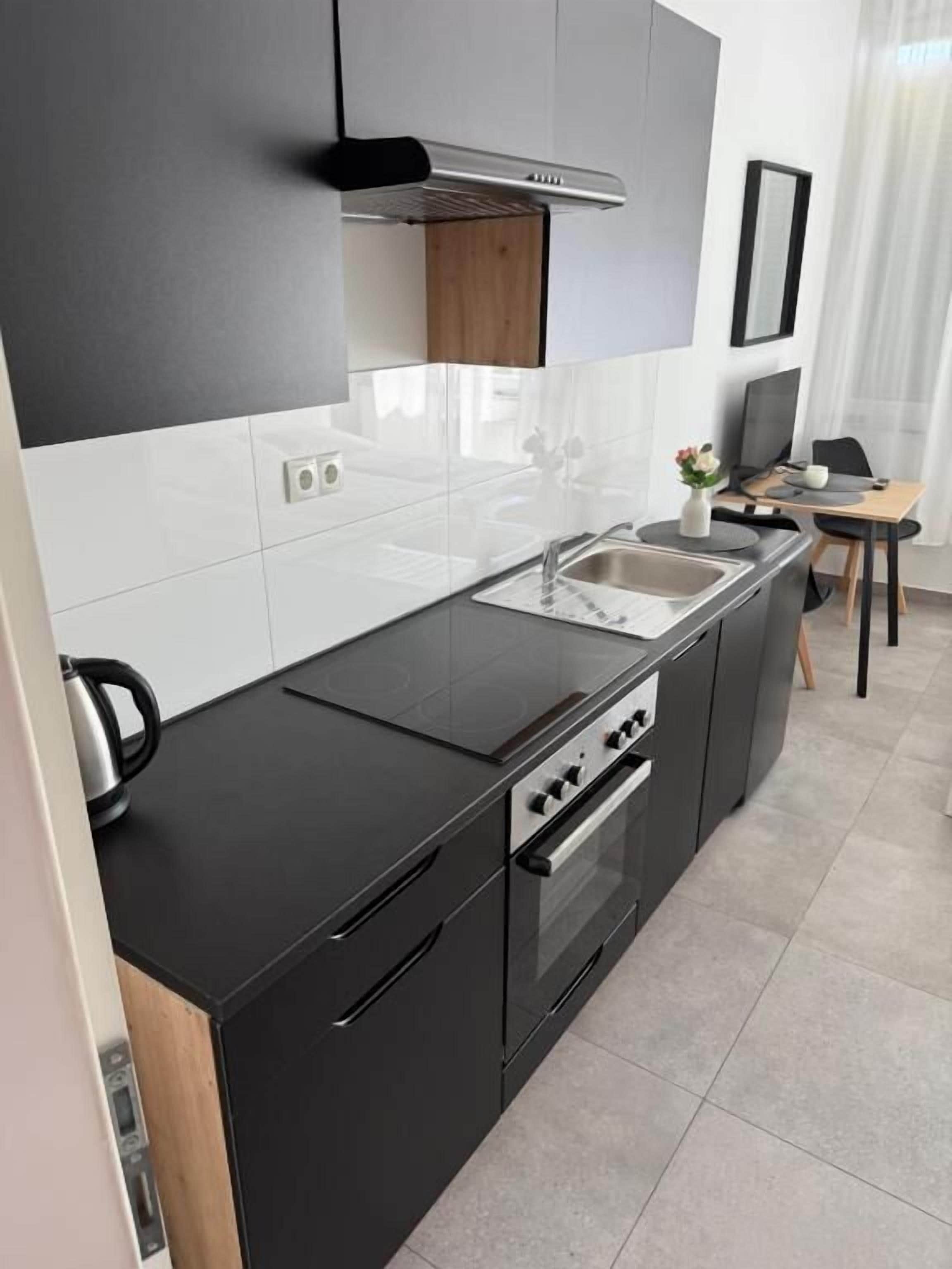 Eine moderne Küche mit schwarzem Arbeitsplatz, Edelstahlgeräten und einem eingebauten Backofen.
