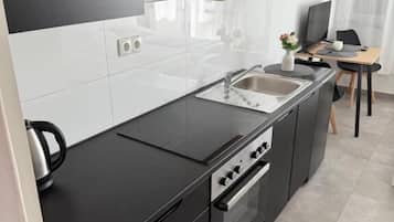 Eine moderne Küche mit schwarzem Arbeitsplatz, Edelstahlgeräten und einem eingebauten Backofen.