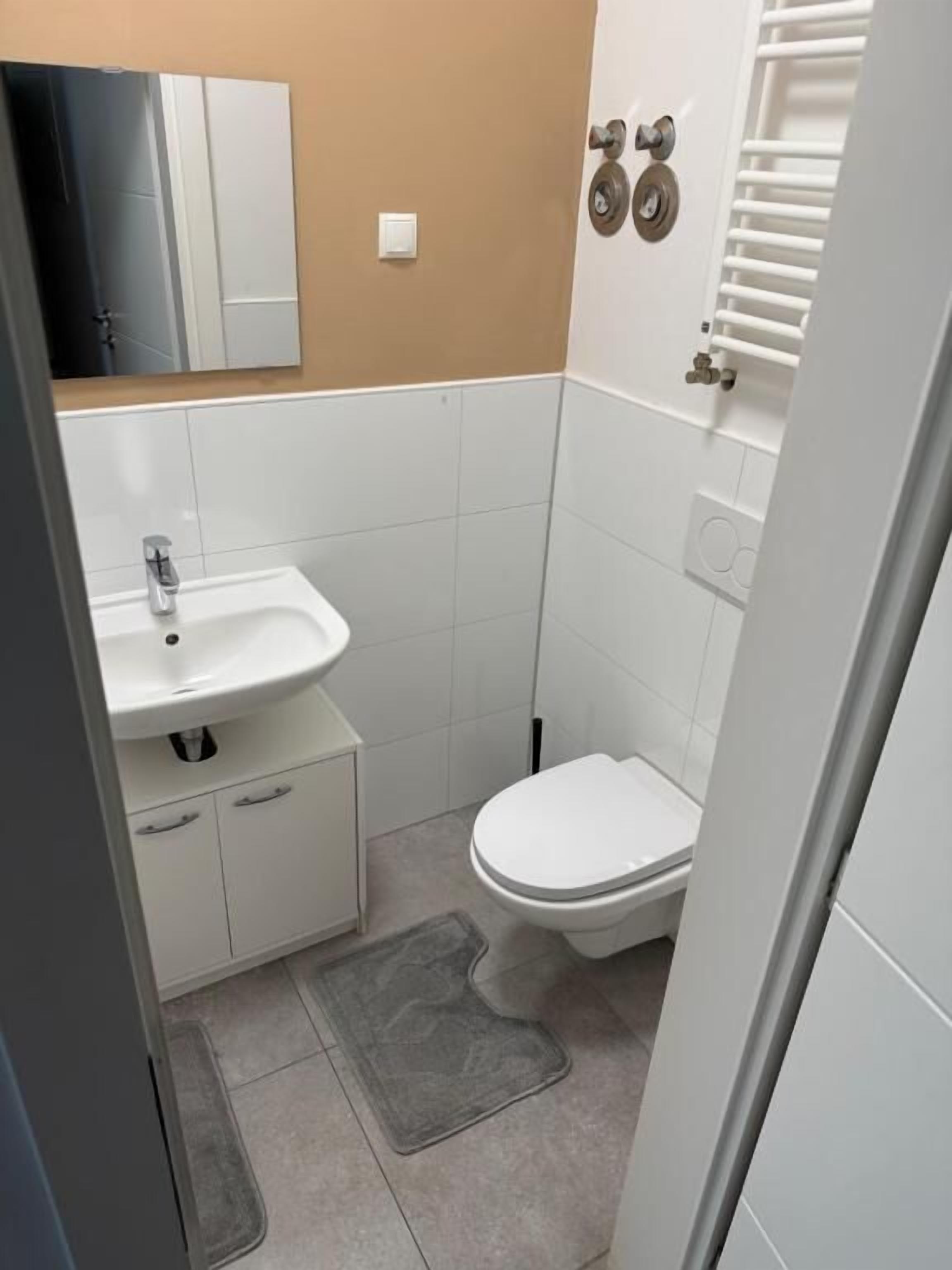 A small bathroom with a white sink, toilet, and a towel rack.