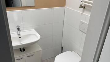 A small bathroom with a white sink, toilet, and a towel rack.