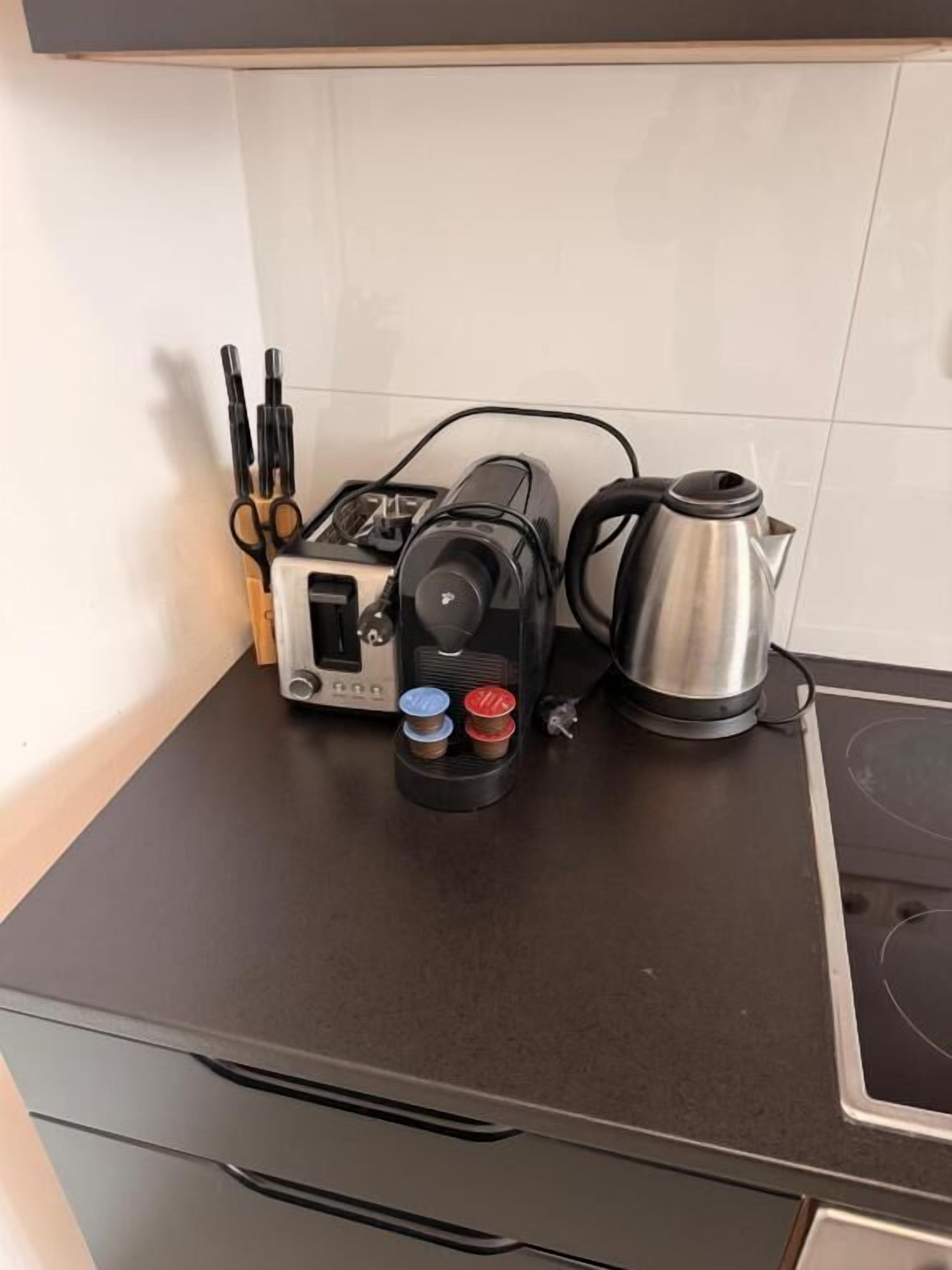 A kitchen counter with a coffee maker, toaster, and a kettle.