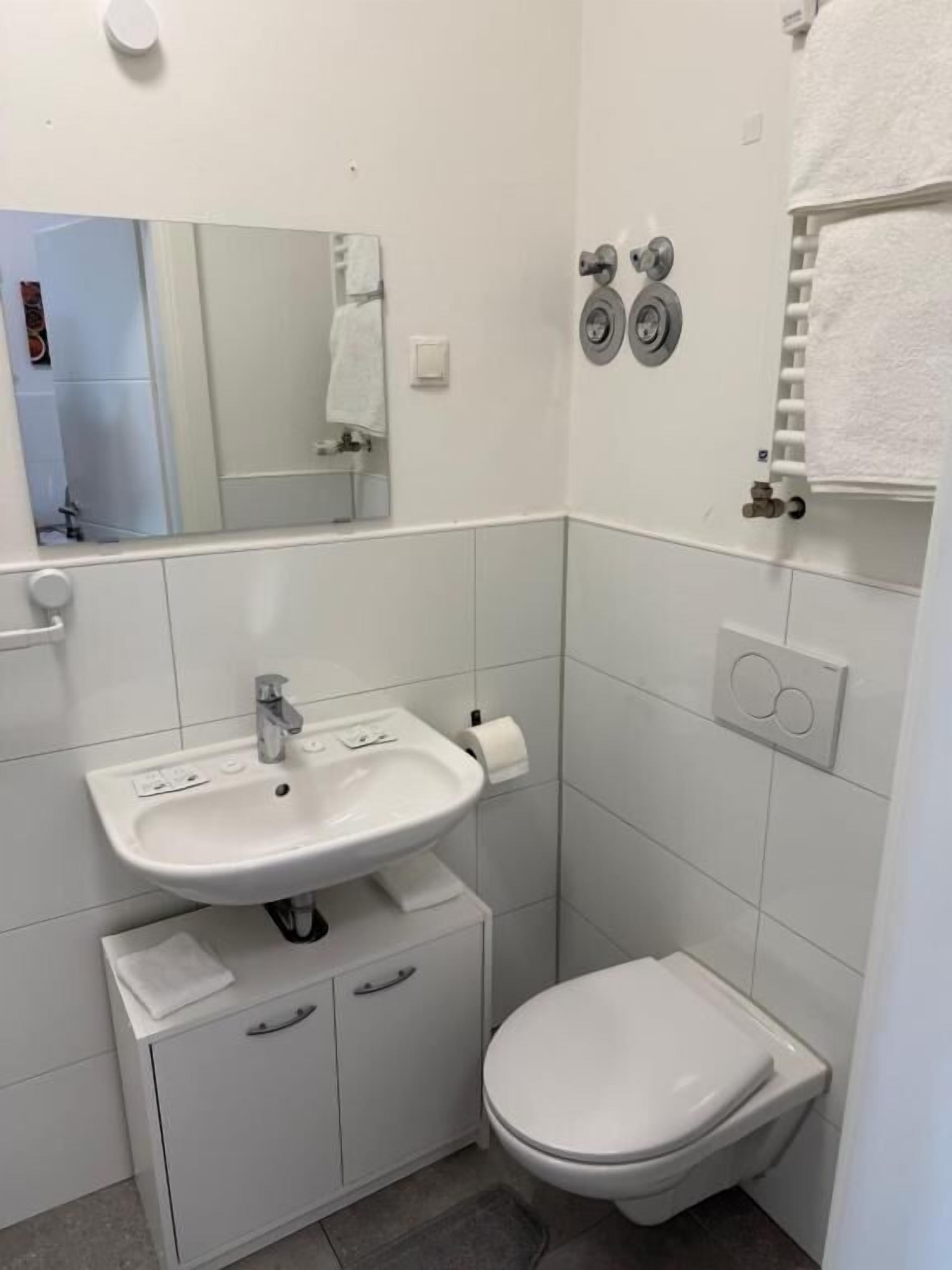 A small, clean bathroom with a white sink, toilet, and mirror.
