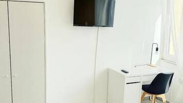Un dormitorio con cama, escritorio, silla, televisión y armario.