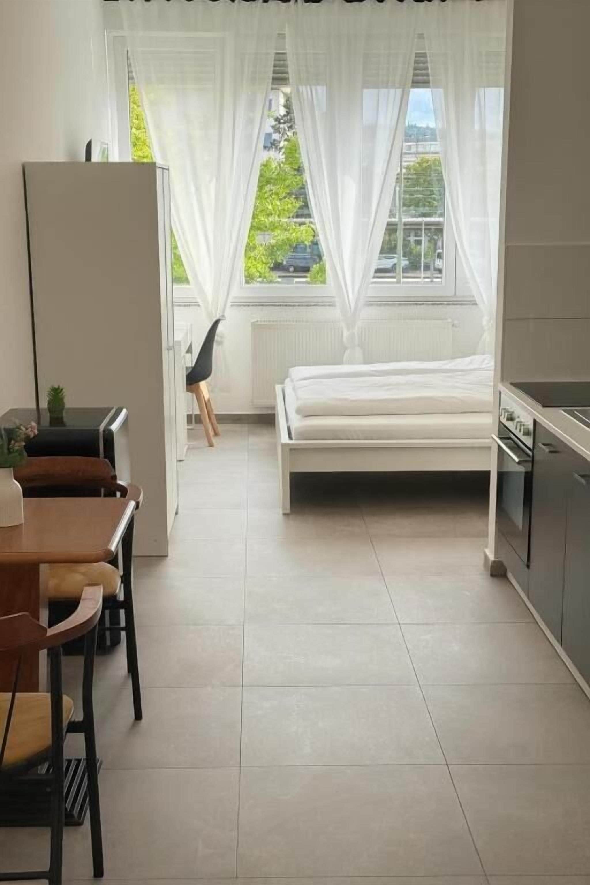 Ein modernes Hotelzimmer mit Bett, Esstisch und Küchenzeile.