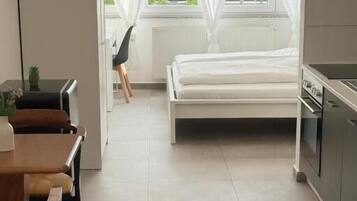 Ein modernes Hotelzimmer mit Bett, Esstisch und Küchenzeile.