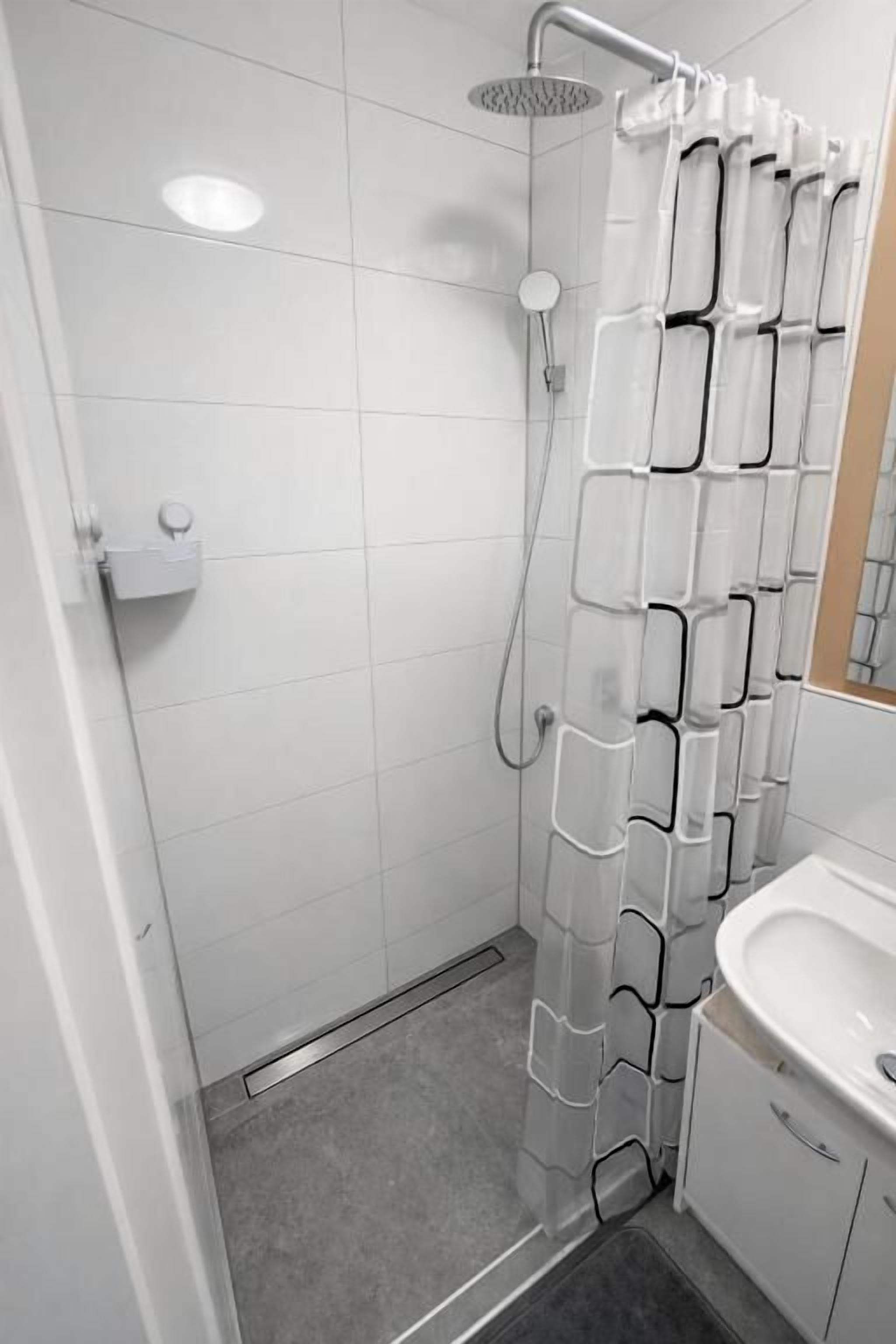 Ein Badezimmer mit Dusche, Waschbecken und Spiegel.