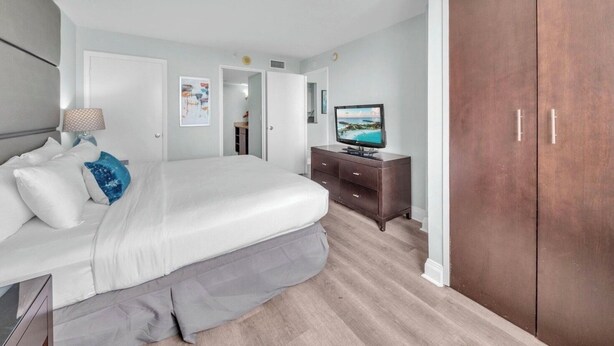Una camera da letto con un letto, una cassettiera, una televisione e un armadio.