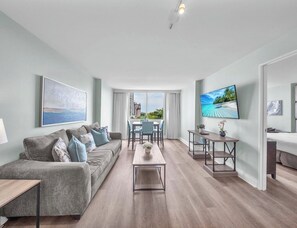 A modern living room with a sofa, coffee table, and a dining area with chairs and a table. - Walk to Paradise - Bright & Cozy 2-Bedroom Fort Lauderdale Beach (Fort Lauderdale)