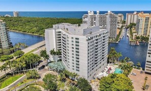 Un hotel moderno de gran altura, con varias plantas, una piscina y un puerto deportivo al fondo.