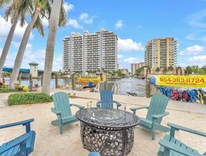A beachfront view with high-rise buildings, a sandy area with chairs, and a jet ski rental sign. - Walk to Paradise - Bright & Cozy 2-Bedroom Fort Lauderdale Beach (Fort Lauderdale)