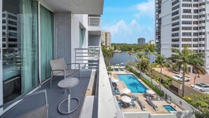 Un balcone con vista su una piscina, poltrone relax e sullo skyline della città.