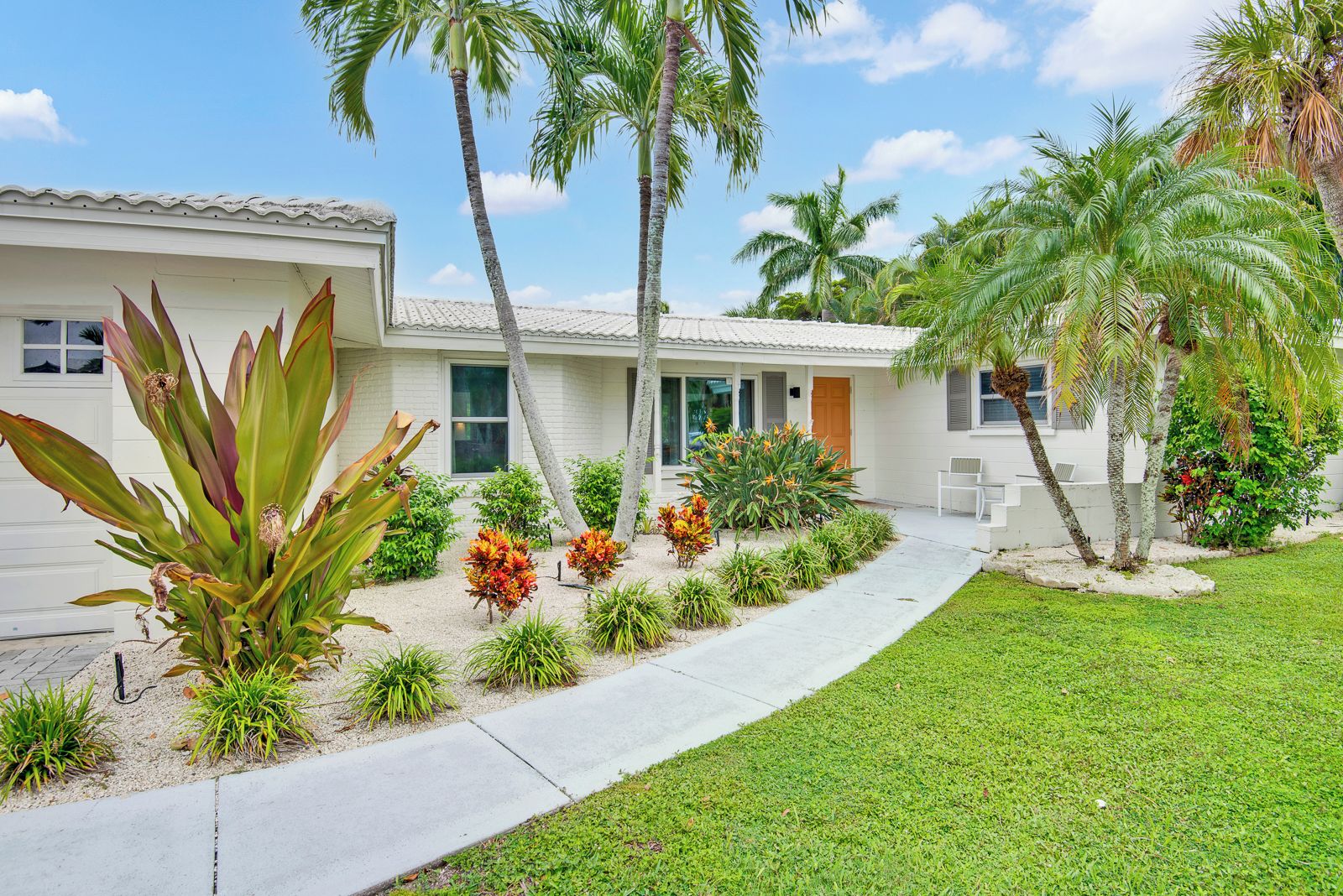 Tropical curb appeal with lush palms and a welcoming front entry