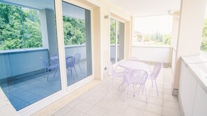 A balcony with a glass door, a table with chairs, and a view of greenery. - 22 Relais du Lac Elite - Italian Homing (Desenzano del Garda)