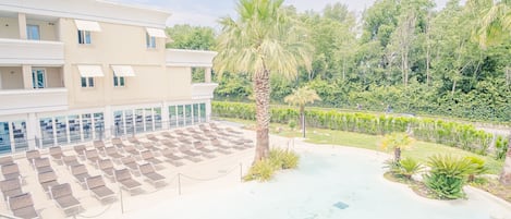 Ett hotell med poolområde, solstolar och en palmpalm.