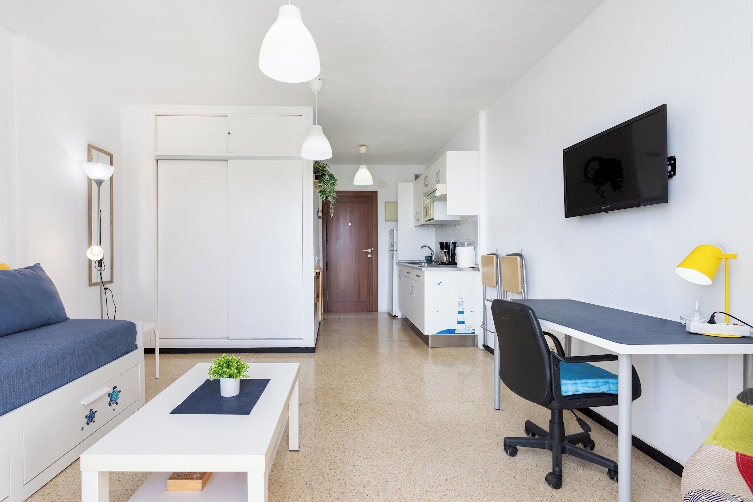 A modern apartment with a living area, kitchenette, and a dining table.