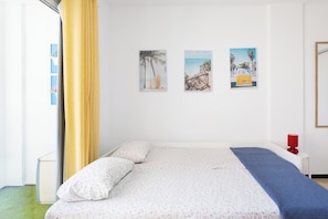 A bedroom with a bed, a nightstand, a red lamp, and three wall-mounted pictures. - Home2Book Sea View Studio & Pool, Caletillas (Las Caletillas)