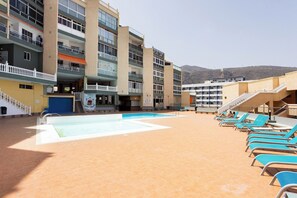 A rooftop pool area with blue lounge chairs, a swimming pool, and a view of mountains in the background. - Home2Book Sea View Studio & Pool, Caletillas (Las Caletillas)