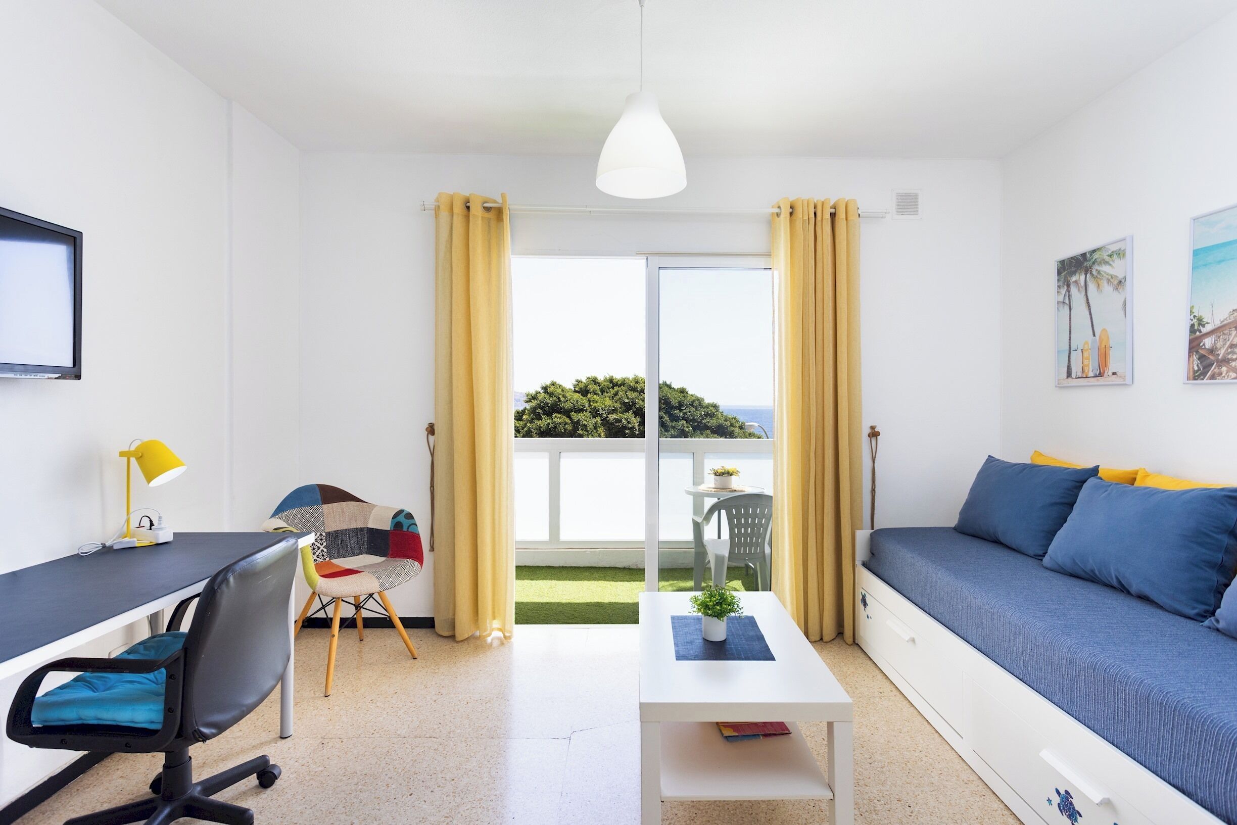 A modern living room with a sofa, a desk, a chair, and a view of the outdoors.