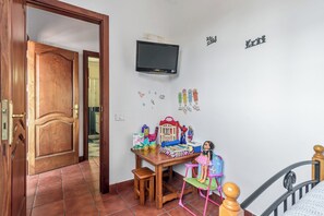 Ein Kinderzimmer mit Holztür, einem an der Wand befestigten Fernseher und verschiedenen Spielsachen und Dekorationen.