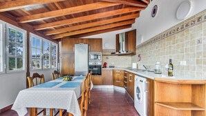 Een keuken met houten kastjes, een inbouwoven, een magnetron en een wasmachine.