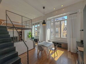 Ein modernes Interieur mit Treppe, Essbereich und großen Fenstern, die einen Blick auf die Stadt bieten.
