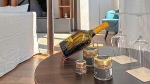 Ein Hotelzimmer mit Bett, einem runden Tisch, einer Champagnerflasche, Weingläsern und kleinen Gewürzbehältern.