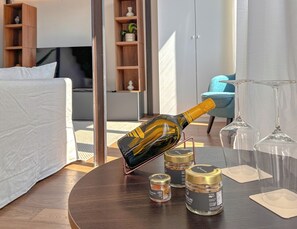 Ein Hotelzimmer mit Bett, einem runden Tisch, einer Champagnerflasche, Weingläsern und kleinen Gewürzbehältern.