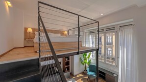 Ein modernes Interieur mit einer Holztreppe, einem Bett, einem Schreibtisch und Blick ins Freie.