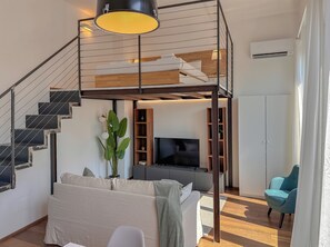 Un espace de vie moderne comprenant un escalier, un canapé, un téléviseur et une plante.