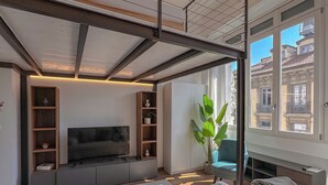 Ein modernes Wohnzimmer mit Flachbildfernseher, Einbauschränken, einem großen Fenster und einer gemütlichen Sitzecke.