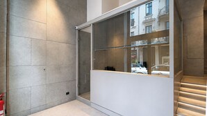 Ein modernes Interieur mit einer Glastrennwand, einem Feuerlöscher und einer Treppe mit beleuchteten Stufen.