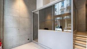 Ein modernes Interieur mit einer Glastrennwand, einem Feuerlöscher und einer Treppe mit beleuchteten Stufen.