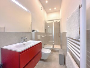 Un baño moderno con lavamanos doble, cabina de ducha con mampara de vidrio y un perchero para toallas.