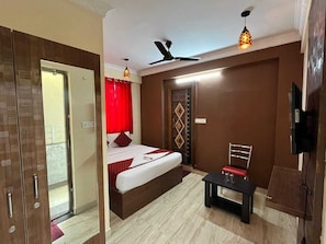 Ein Schlafzimmer mit einem Bett, einem Schreibtisch, einem Sessel, einem Fernseher und einem Deckenventilator.