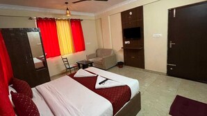 A hotel room with a bed, a chair, a desk, a TV, and a wardrobe. - Tanish Stay Inn (Bengaluru)