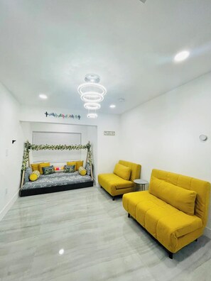 A modern living room with a sofa, a bed with decorative pillows, and a ceiling light fixture. - Lakefront home with private pool near Miami (Miramar)