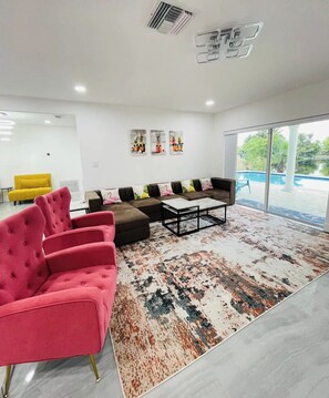 Ein modernes Wohnzimmer mit einer Eckcouch, einem Couchtisch und einem farbenfrohen Teppich.