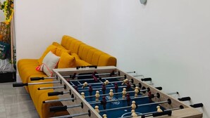 A foosball table in a room with a yellow sofa and a wall-mounted plant. - Lakefront home with private pool near Miami (Miramar)