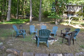 An outdoor seating area with several Adirondack chairs arranged around a fire pit.