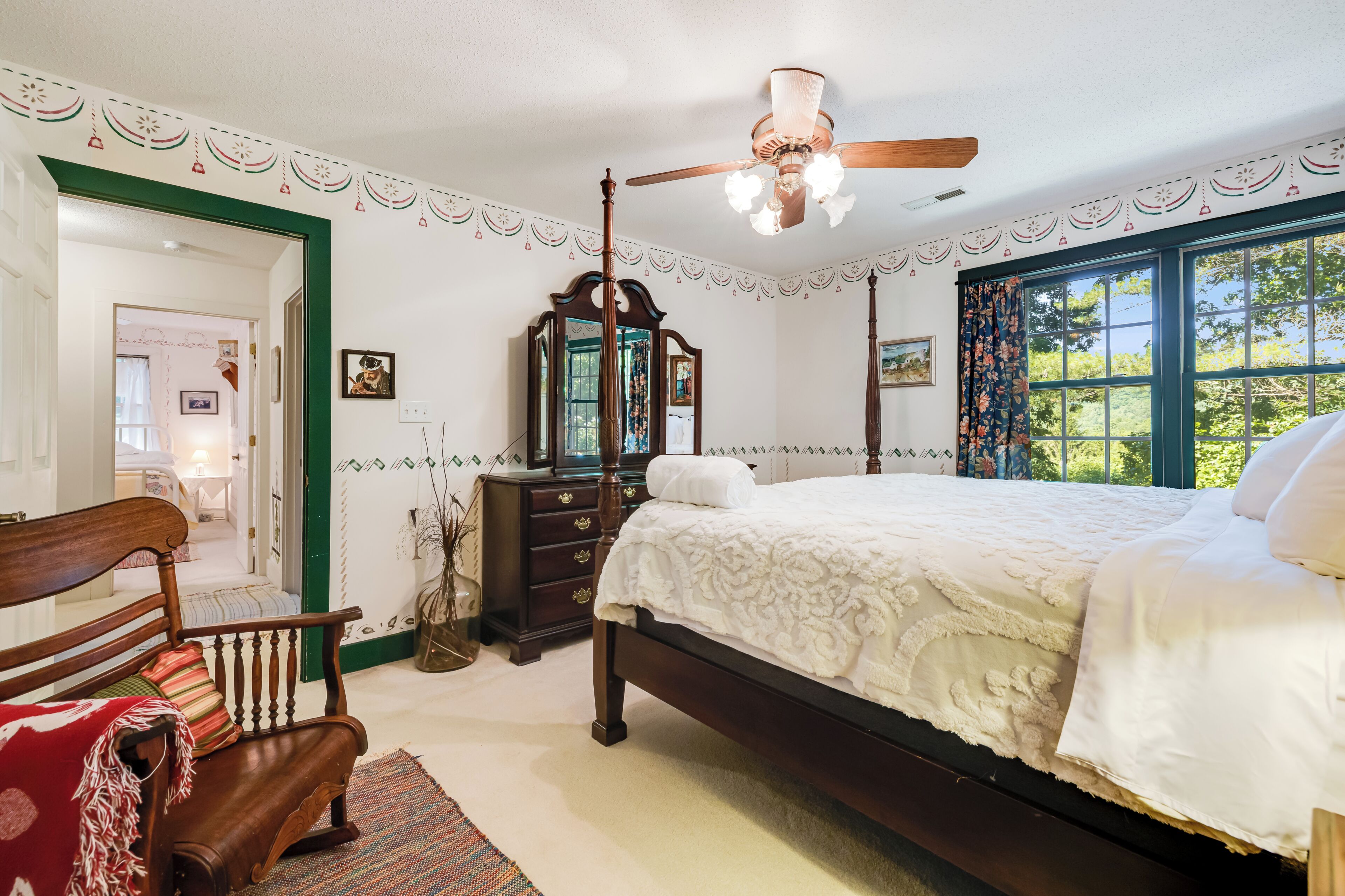 A bedroom with a four-poster bed, a wooden chair, a dresser, and a mirror.