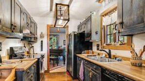 A kitchen with wooden cabinets, a black refrigerator, and a wooden countertop.