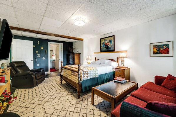 Una habitación con cama, sofá, sillón, mesa y televisión.