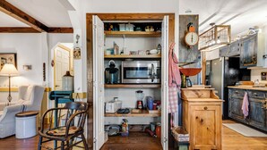 A compact kitchen with a microwave, toaster, and wooden cabinets.