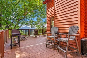 Une terrasse en bois, aménagée avec du mobilier d’extérieur, notamment des chaises et une table, qui offre une vue sur un paysage montagneux.