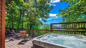 A hot tub on a wooden deck with outdoor furniture and a view of a forested area. - Stunning MTN and Valley Views! 3BR*Hot Tub*Privacy (Sevierville)